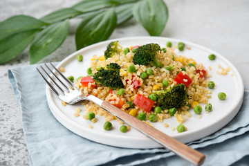 Lenten dish. Bulgur with vegetables in a plate. Pilaf from bulgur, broccoli, green peas, bell peppers and corn.
