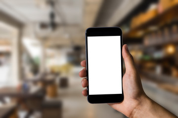 Hand holding white mobile phone with blank white screen  in cafe.