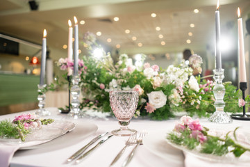 Closeup Table setting with plates and tableware, adorned with flowers. Floral decoration for wedding ceremony romance dining. Wedding banquet , festive decor. Concept of service and catering.