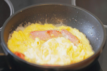 Fried eggs with sausage in frying pan