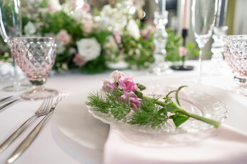 Closeup Table setting with plates and tableware, adorned with flowers. Floral decoration for wedding ceremony romance dining. Wedding banquet , festive decor. Concept of service and catering.