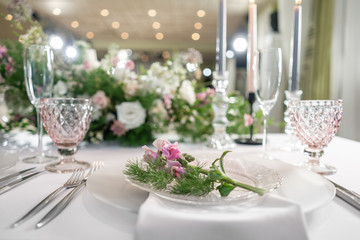Closeup Table setting with plates and tableware, adorned with flowers. Floral decoration for wedding ceremony romance dining. Wedding banquet , festive decor. Concept of service and catering.