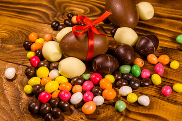 Chocolate easter eggs and multicolored candies on wooden table