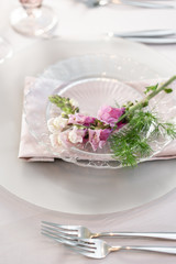 Closeup Table setting with plates and tableware, adorned with flowers. Floral decoration for wedding ceremony romance dining. Wedding banquet , festive decor. Concept of service and catering.
