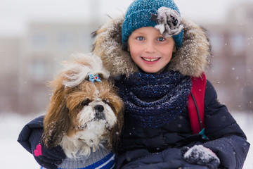 Portrait of a cute girl with a dog in a winter park. Girl hugging dog.