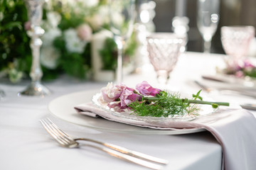 Closeup Table setting with plates and tableware, adorned with flowers. Floral decoration for wedding ceremony romance dining. Wedding banquet , festive decor. Concept of service and catering.