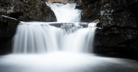 Obraz premium Scene with peaceful waterfall among the mountains