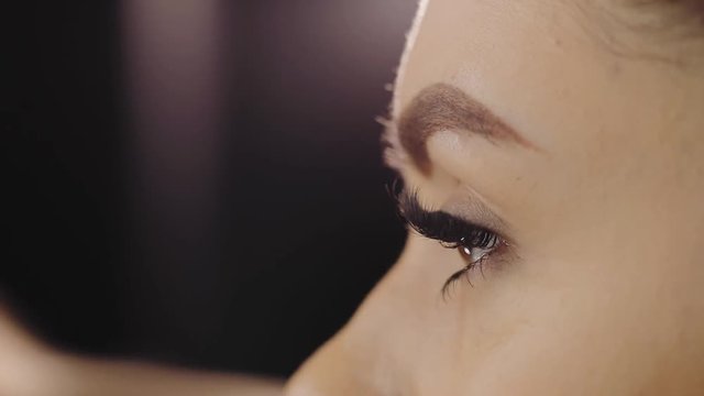 Tattoo artist contours eyebrows with a pencil