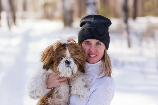 Outdoors lifestyle close up image of stunning woman hugging dog in the winter park.