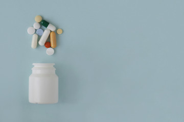 Pills, tablets and capsules and a bottle on a blue background. Copy space for text.
