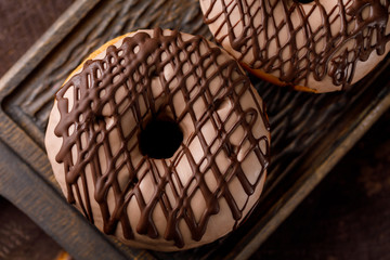 Concept of cooking, baking and food - close-up. Milk chocolate glazed donuts on a decorative board top view.