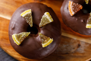 Concept of cooking, baking and food - close-up. Chocolate coated donuts with marmalade decoration top view.