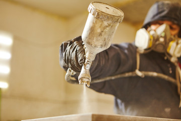 Close up image of carpenter painting with a paint spray gun