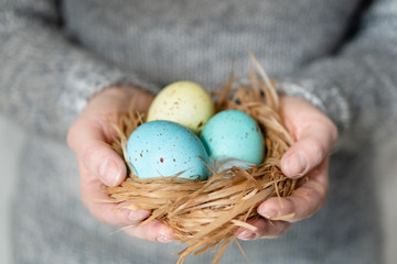 Woman with her hands full of brightly colored Easter eggs in the nest.