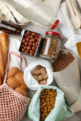 Meal in eco cotton bags, glass and paper packaging on table in the kitchen from market. zero waste shopping concept. ban plastic, Bread, nuts, sugar, buckwheat, pasta, beans