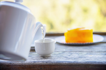 Hot eat cup and orange cake with green nature background - food and drink in wild nature concept