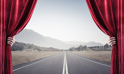 Asphalt road behind red curtain and hand holding it