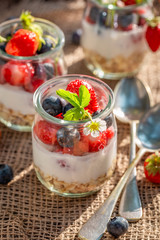 Homemade oat flakes in jar with yoghurt and berries