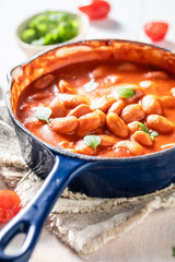 Tasty baked beans with tomato sauce and fresh herbs