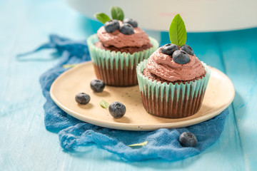 Muffin with blueberries and chocolate cream on blue table