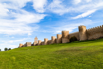 View of the medieval city walls surrounding the city of Avila, Spain, and the green lawn in front of Puerta del Carmen. Called the Town of Stones and Saints, Avila is a UNESCO World Heritage Site © giusparta