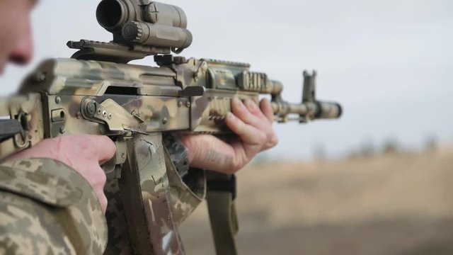 Brave man shooting from an automatic rifle with an optical sight in slo-mo  