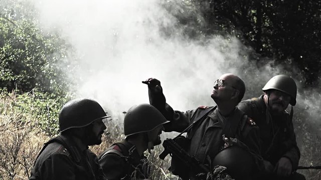 Soldiers sit in meadow &ndash; heavy smoke flows in background