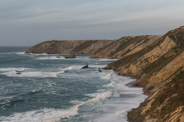 Wavy sea . Breathtaking view of a beach and the cliffs.