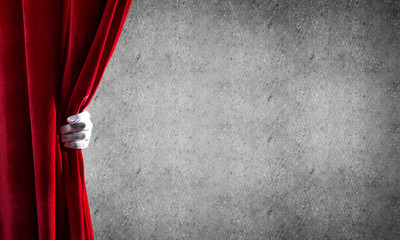 Concrete wall behind drapery curtain and hand opening it
