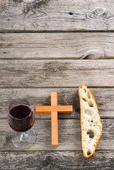 wooden cross and red wine with a slice of bread on old wood table