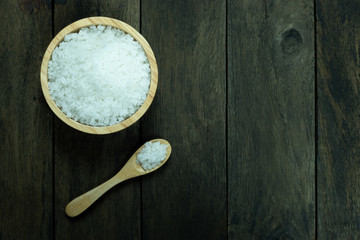 salt in a bowl and spoon on wood background