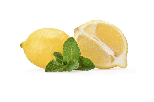 Still life of half a fresh yellow lemon and a whole lemon in profile with a sprig of green peppermint