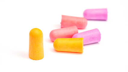Yellow, violet and pink earplugs on a white background.