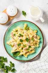 Pasta carbonara with zucchini in craft plate on white. 