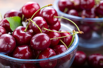 sweet red cherries in a plate on a wooden background.