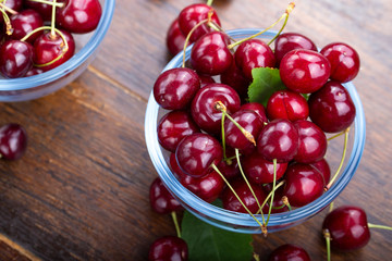sweet red cherries in a plate on a wooden background.