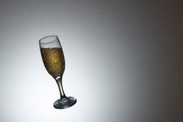 Champagne glass in midair on gray background