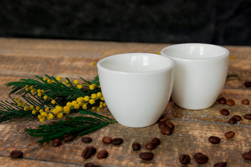 Coffee cups with coffee beans and a sprig of mimosa