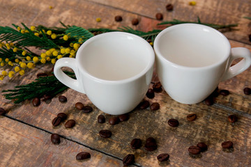Obraz na płótnie Canvas Coffee cups with coffee beans and a sprig of mimosa