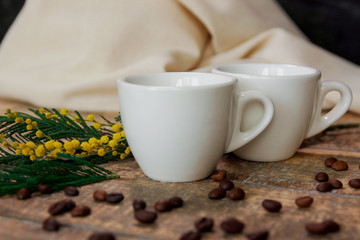 Coffee cups with coffee beans and a sprig of mimosa