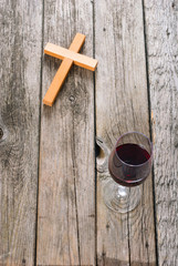 wooden cross and glass of red wine on old wood table