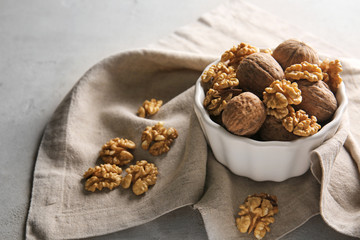 Bowl with walnuts on grey background