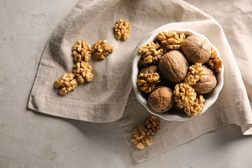 Bowl with walnuts on grey background