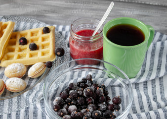 Cookies and berries on a bowl, tea in a green cup.