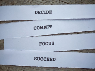 Motivational and inspirational words - Decide, Commit, Focus,Succeed written on papers and placed on a wooden table.