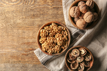 Plates with tasty walnuts on wooden table