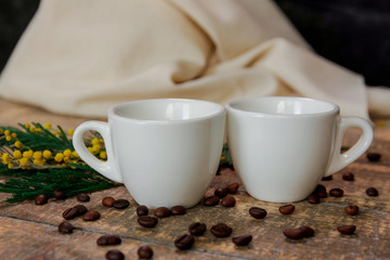 Coffee cups with coffee beans and a sprig of mimosa