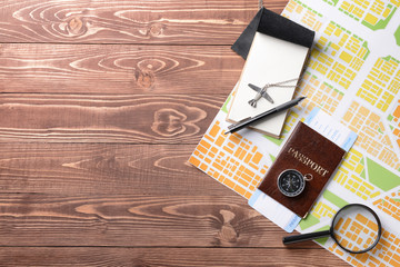 Map with passport, compass and magnifier on wooden table