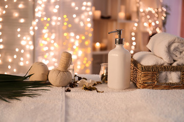 Towels, cosmetics and herbal bags on table in spa salon