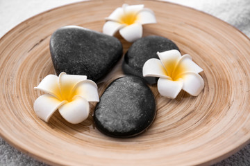 Fototapeta na wymiar Spa stones and beautiful flowers on plate